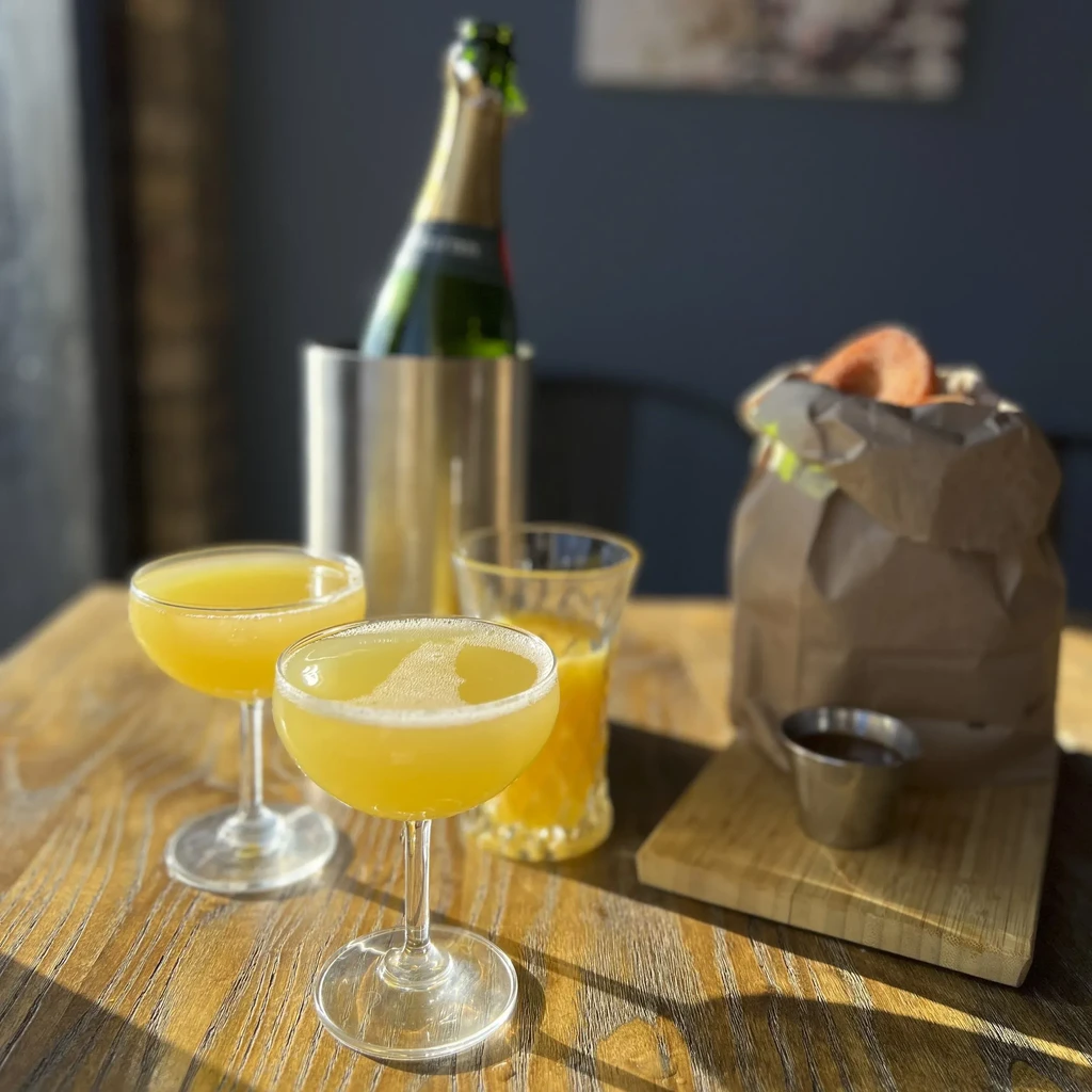 Brunch spread with champagne, mimosas, orange juice, and fried snacks.