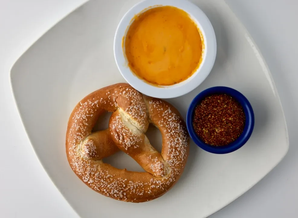 Pretzel with salt crystals, cheese sauce, and whole grain mustard.