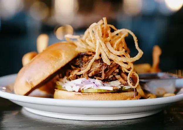 Pulled pork sandwich with fried onions, red onions, and pickles.