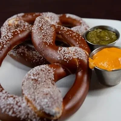 Soft pretzels with two dipping sauces on a white plate.