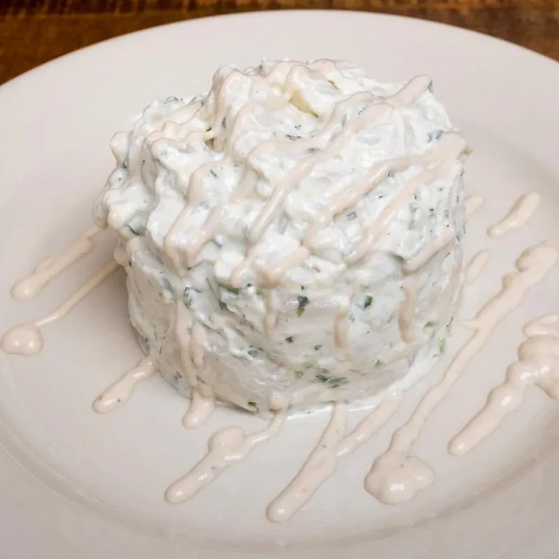 Cylindrical food item with green flecks, drizzled with pink sauce.