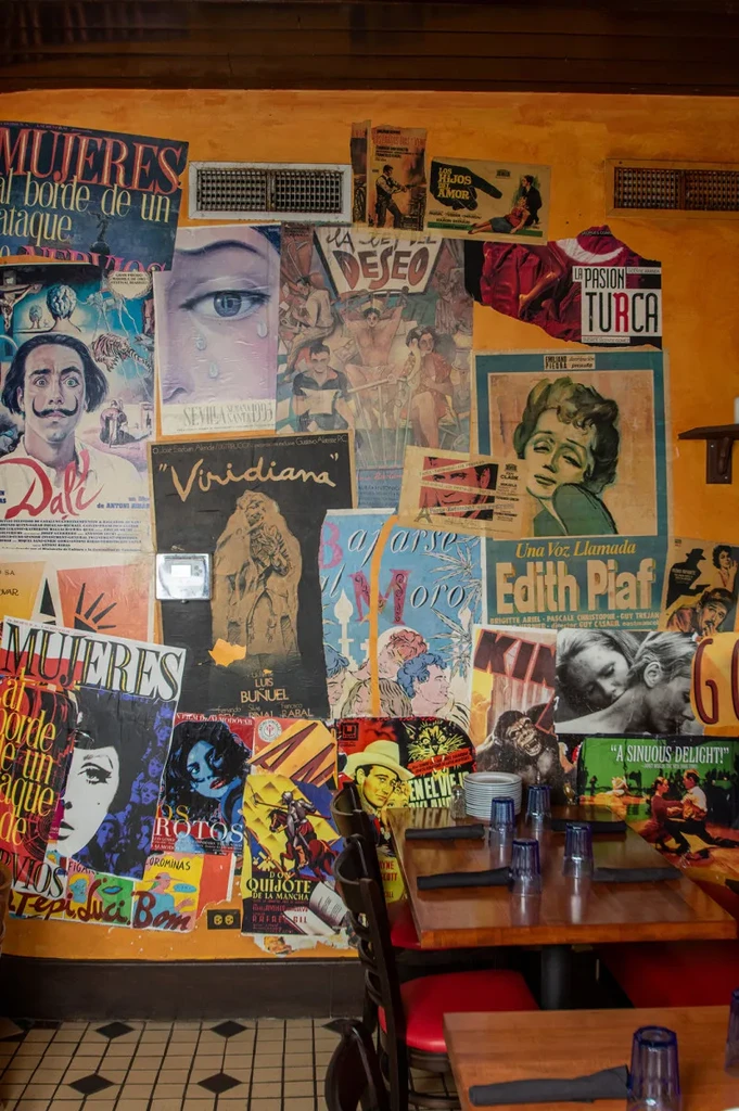 Restaurant with an orange wall covered in vintage Spanish movie posters.