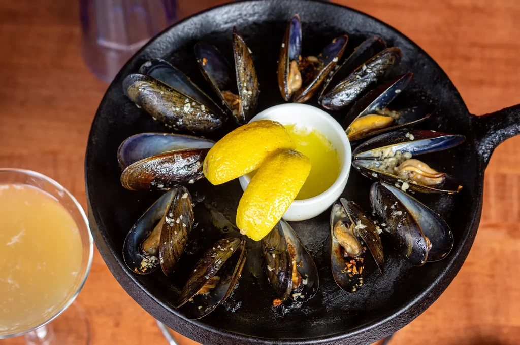 Steamed mussels in a cast-iron pan with butter and lemon.