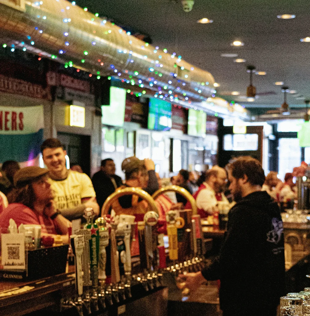 Interior view of a lively bar with beer taps and patrons.