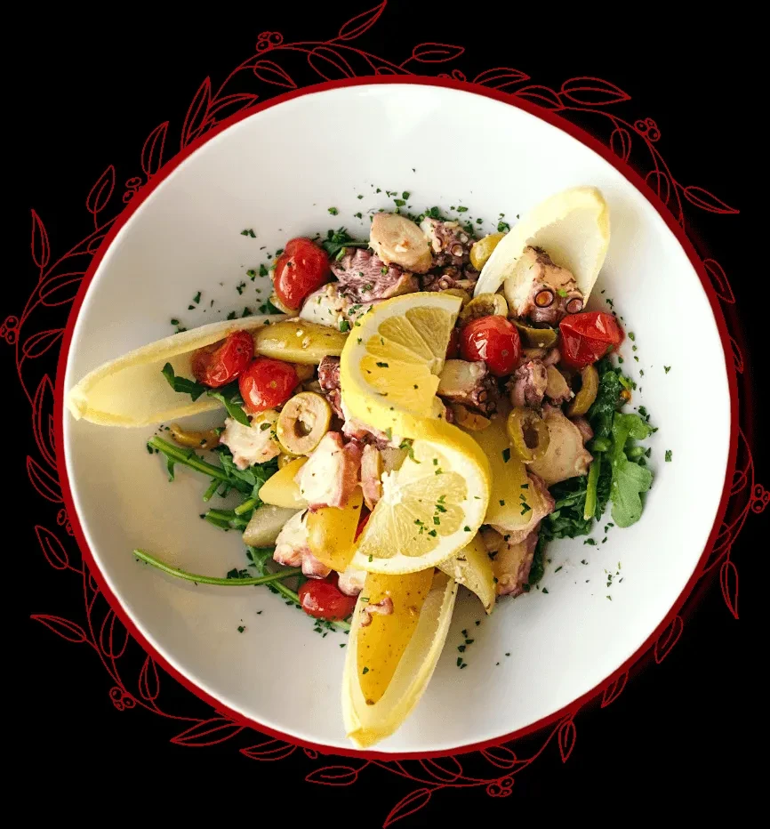 Overhead shot of seafood salad with octopus, tomatoes, olives, and lemon.