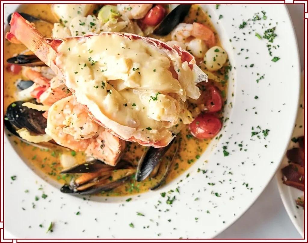 Luxurious seafood dish with halved lobster tail, shrimp, mussels, and tomatoes.