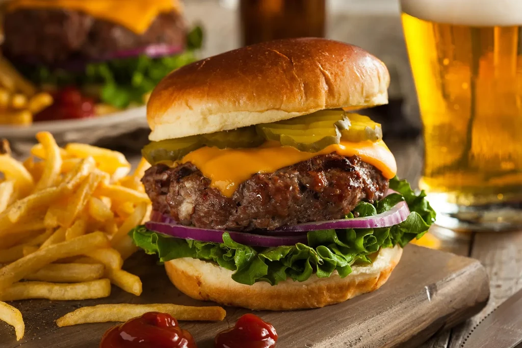 Cheeseburger and fries on a wooden surface with ketchup.
