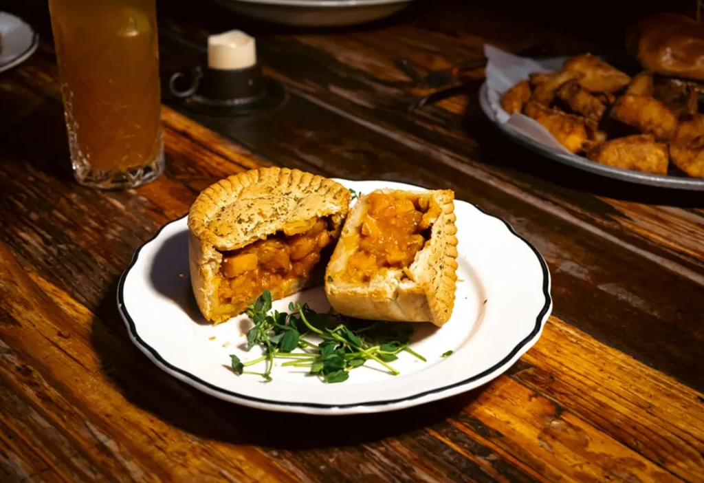 Savory pie cut in half, revealing filling, on a white plate.