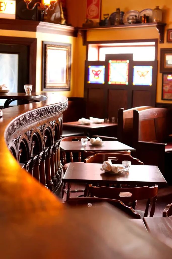 Empty restaurant interior with dark wood furniture and warm lighting.