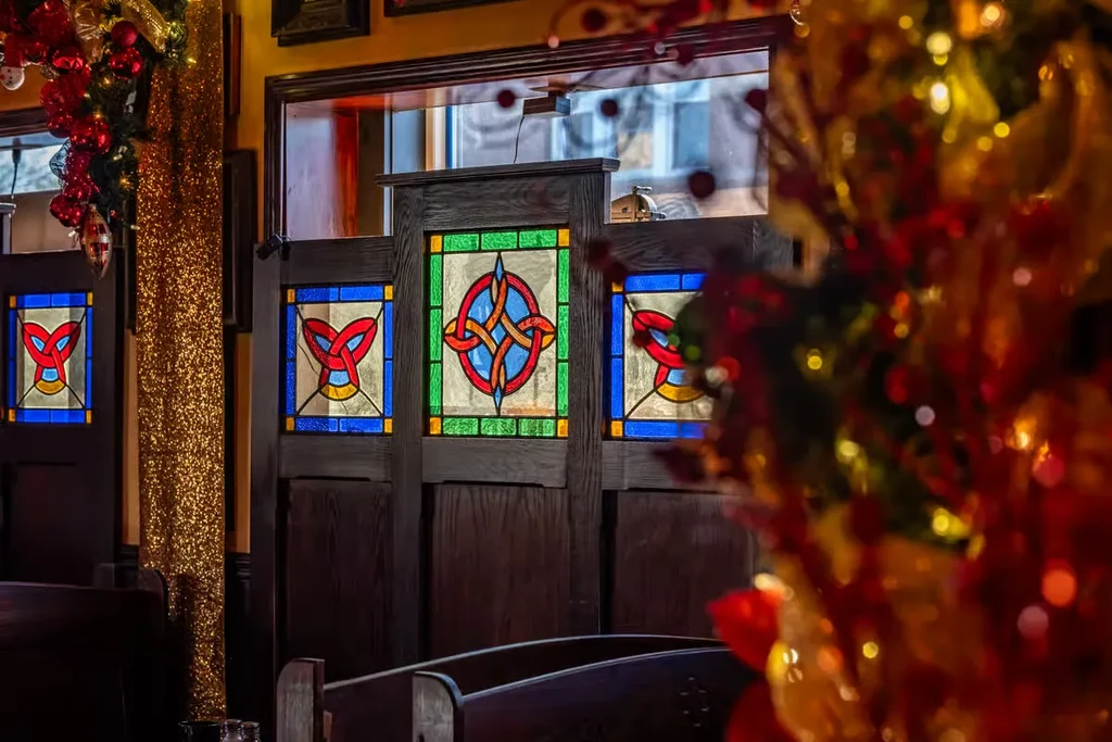 Restaurant interior with festive decor and three stained-glass panels.