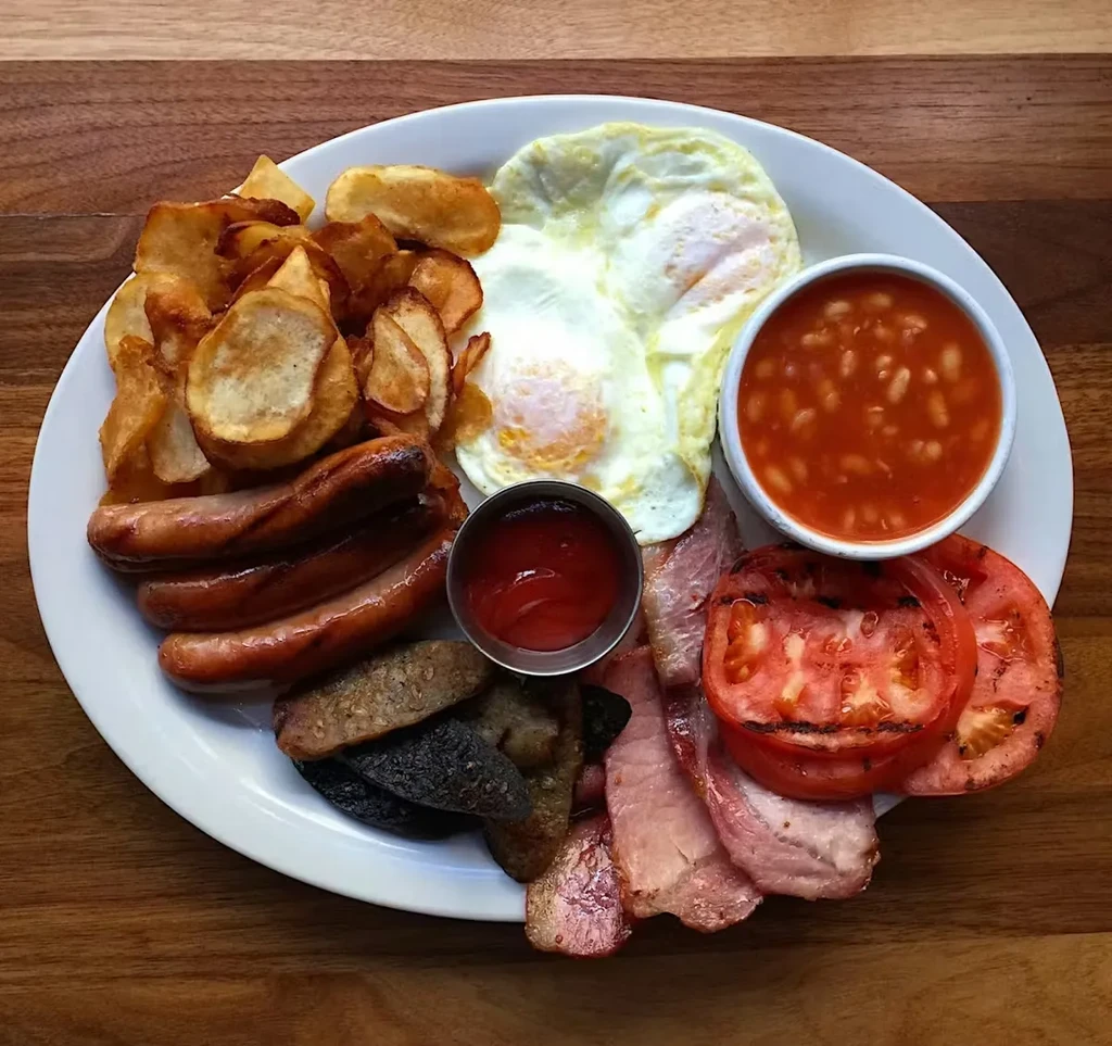 Full English breakfast with eggs, bacon, sausage, beans, and chips.