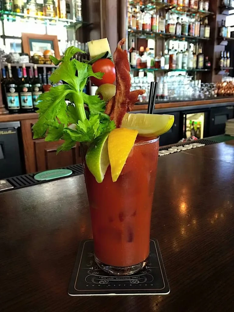 Bloody Mary cocktail with extensive garnishes on a wooden bar.