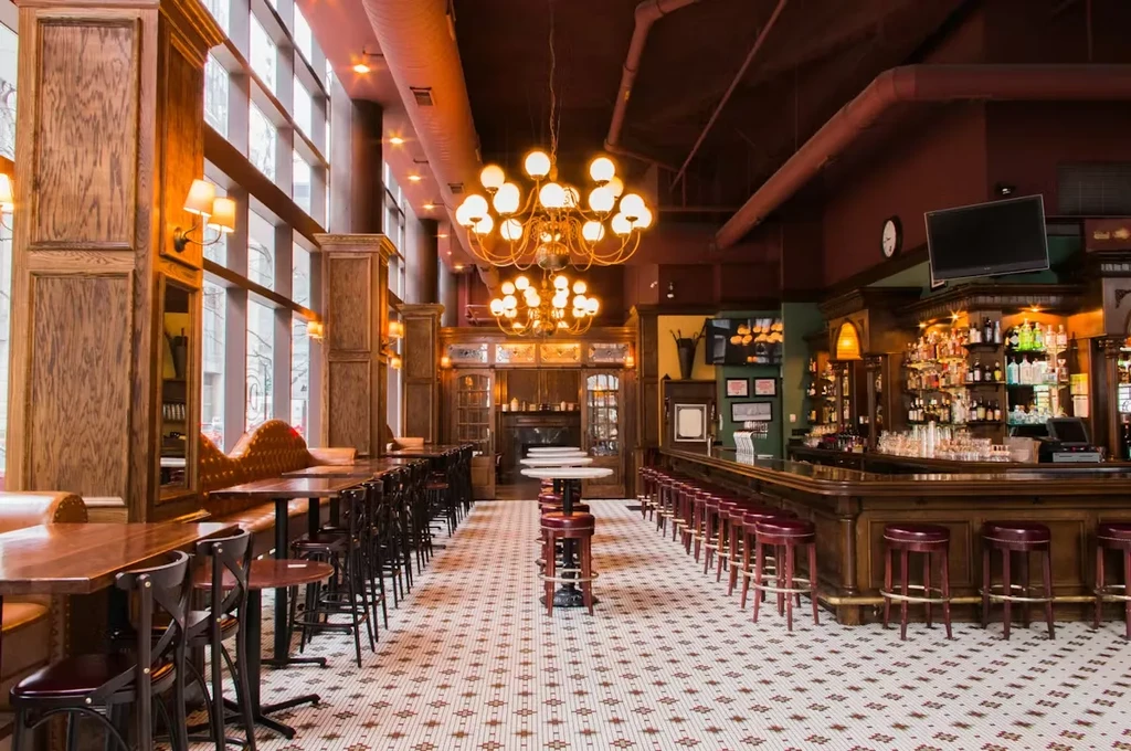 Spacious, empty restaurant with a bar, booths, high-top tables.