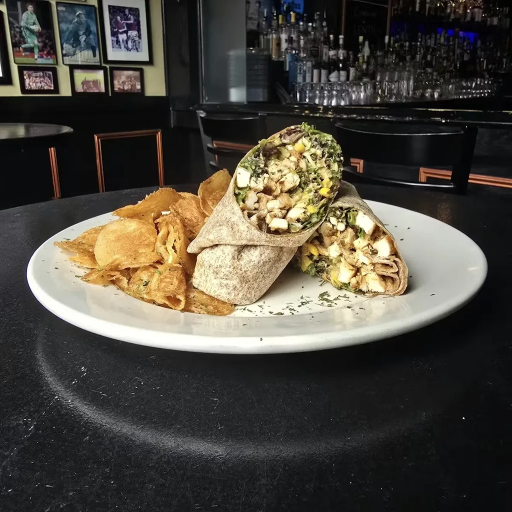 Chicken wrap with chips on a plate in a restaurant.