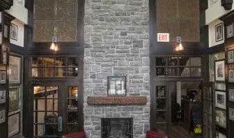 Rustic lodge interior with stone fireplace and dark wood walls.