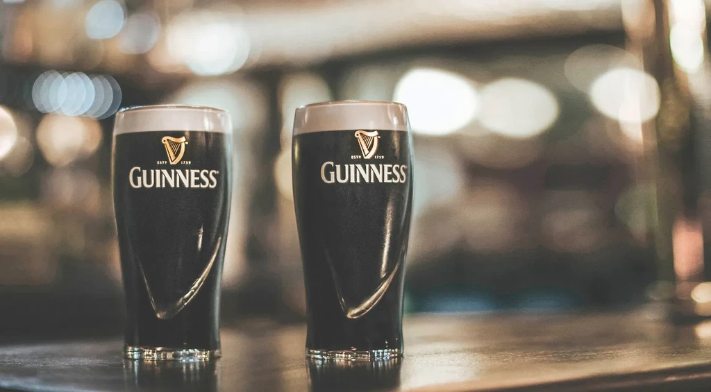 Two glasses of Guinness beer on a polished bar top.