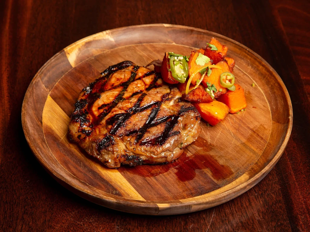 Grilled steak with roasted vegetables, chili peppers, and herbs.