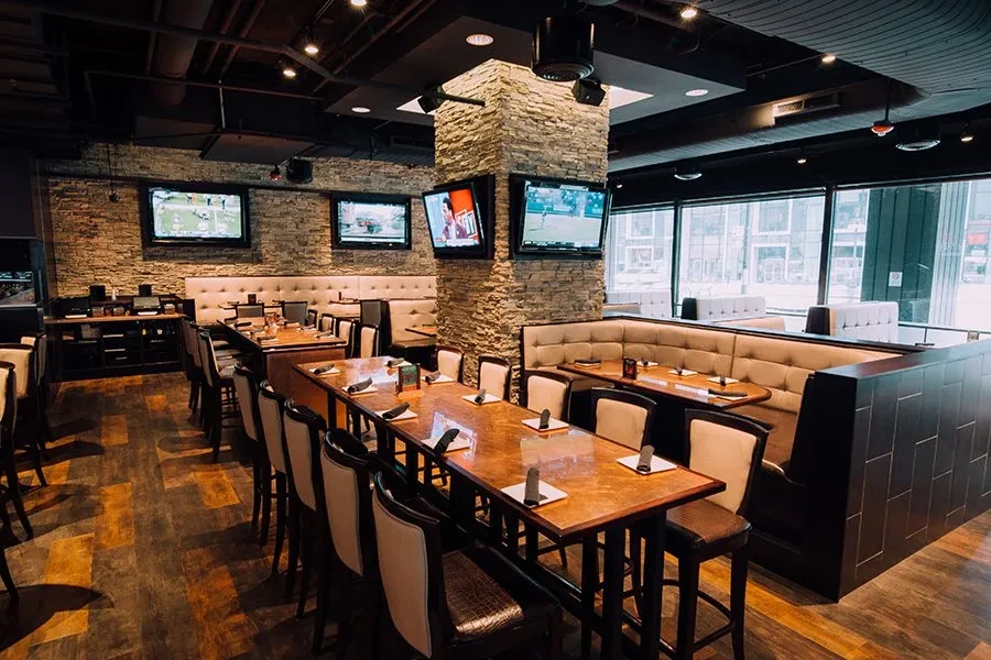 Interior of a modern sports bar with various seating and TVs.