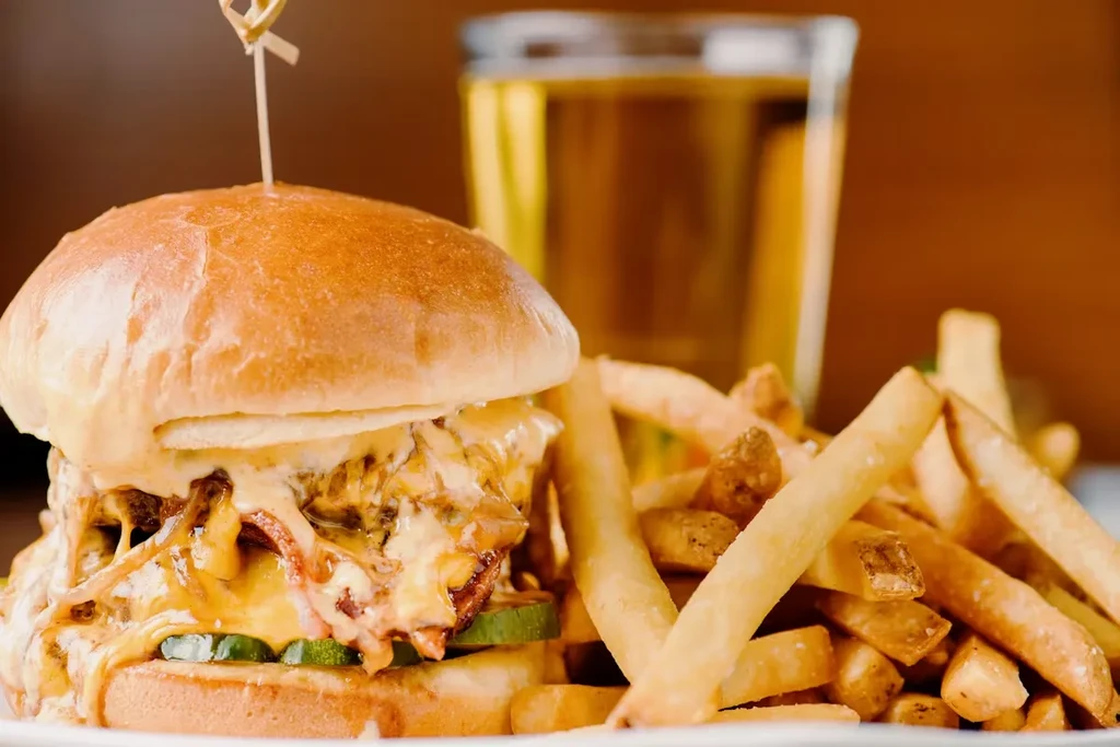 Gourmet burger with melted cheese, pickles, and golden french fries.