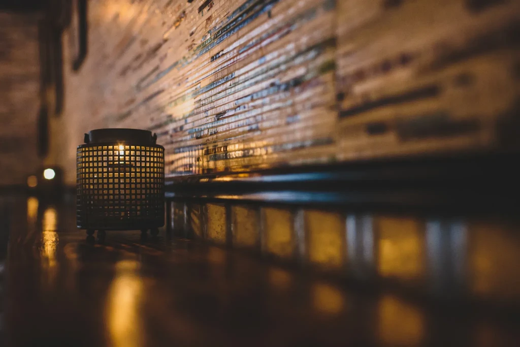 Decorative metal lantern emitting warm light on a polished wooden surface.