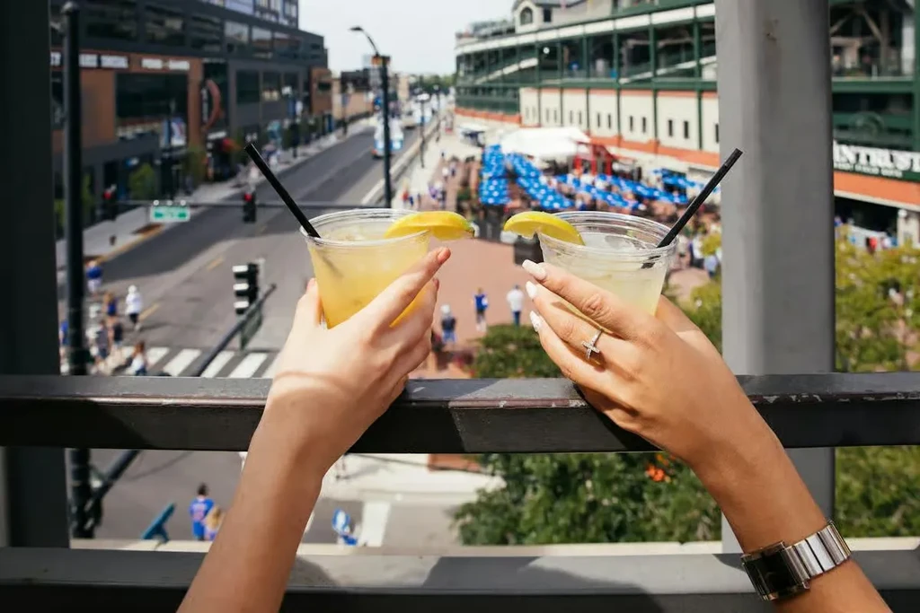 Two hands hold drinks with lemons over a city street.