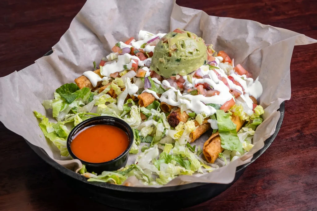 Taquitos with lettuce, pico de gallo, sour cream, and guacamole.