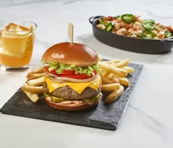 Gourmet burger and fries on a black slate plate.