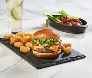 Burger and tater tots on a slate plate.
