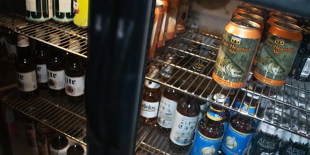 Inside a refrigerated display case with various alcoholic beverages.
