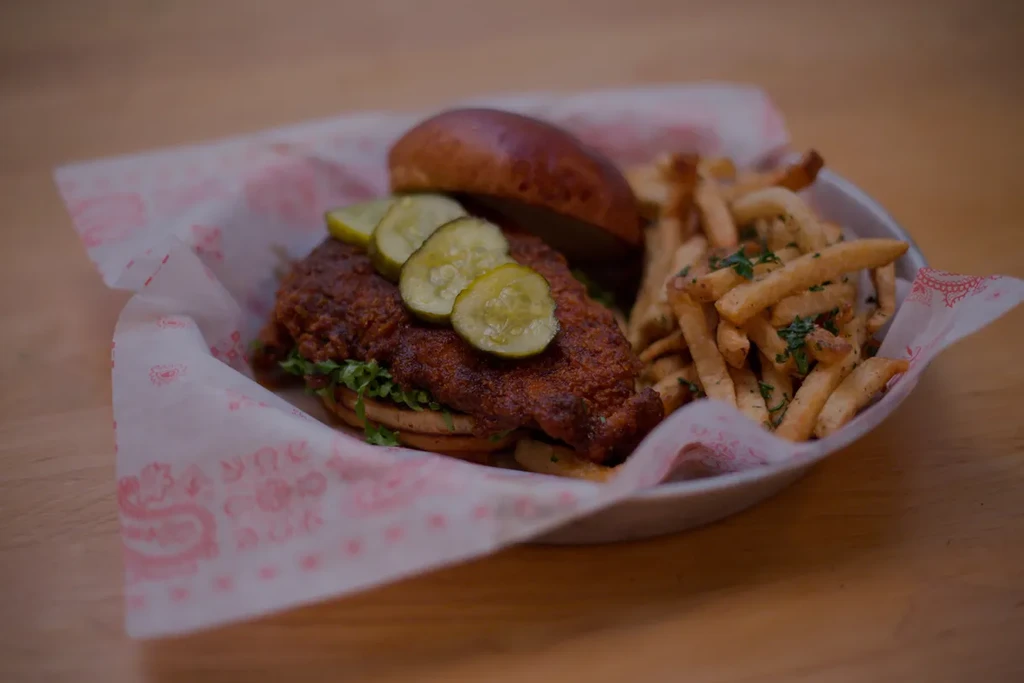 Fried chicken sandwich with pickles, lettuce, and french fries.