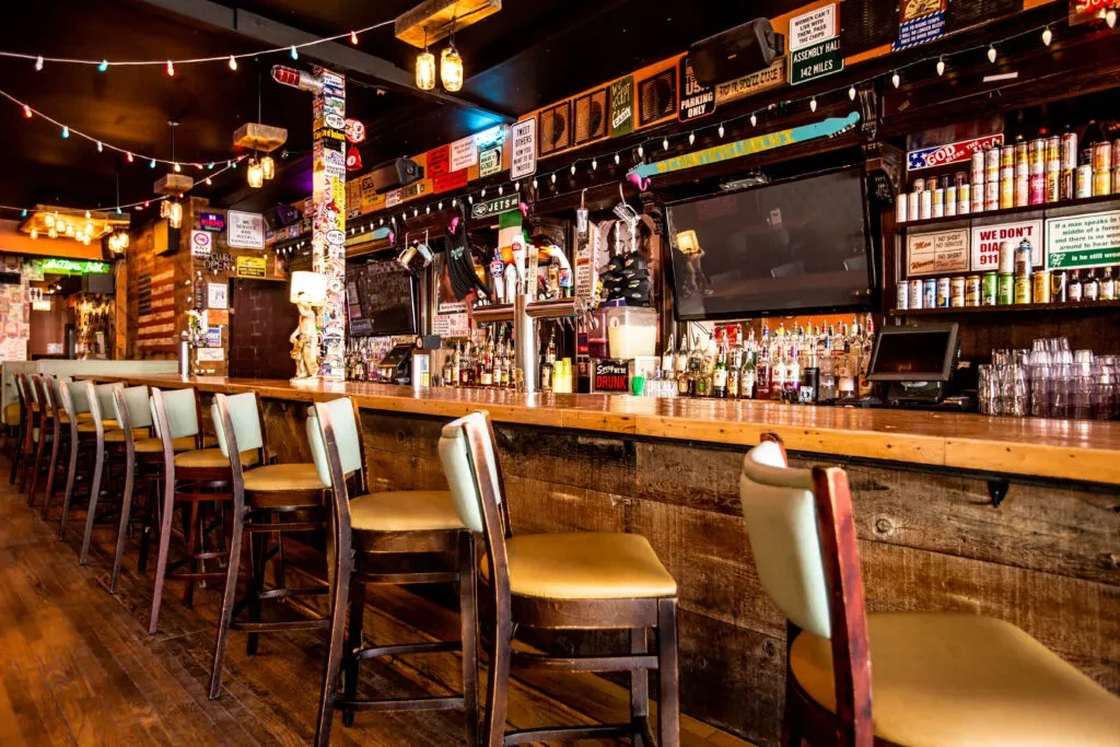 A vibrant, rustic-themed bar interior with a long wooden counter.