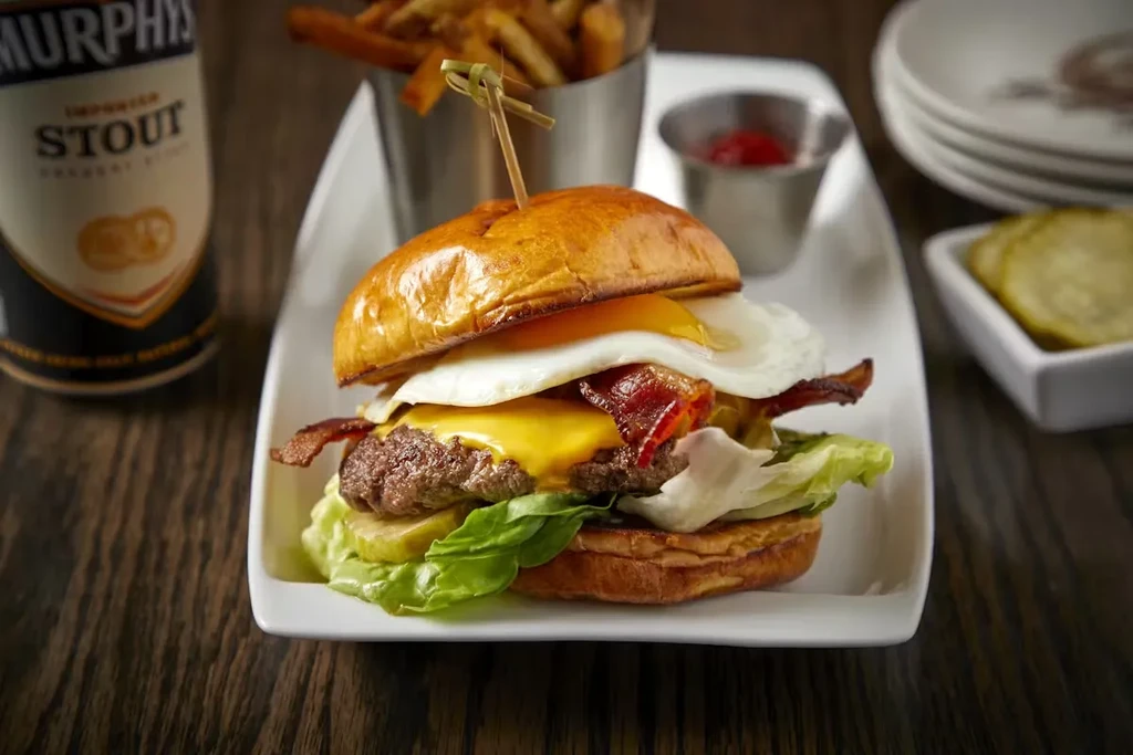 Gourmet burger with fries, ketchup, pickles, and stout beer.