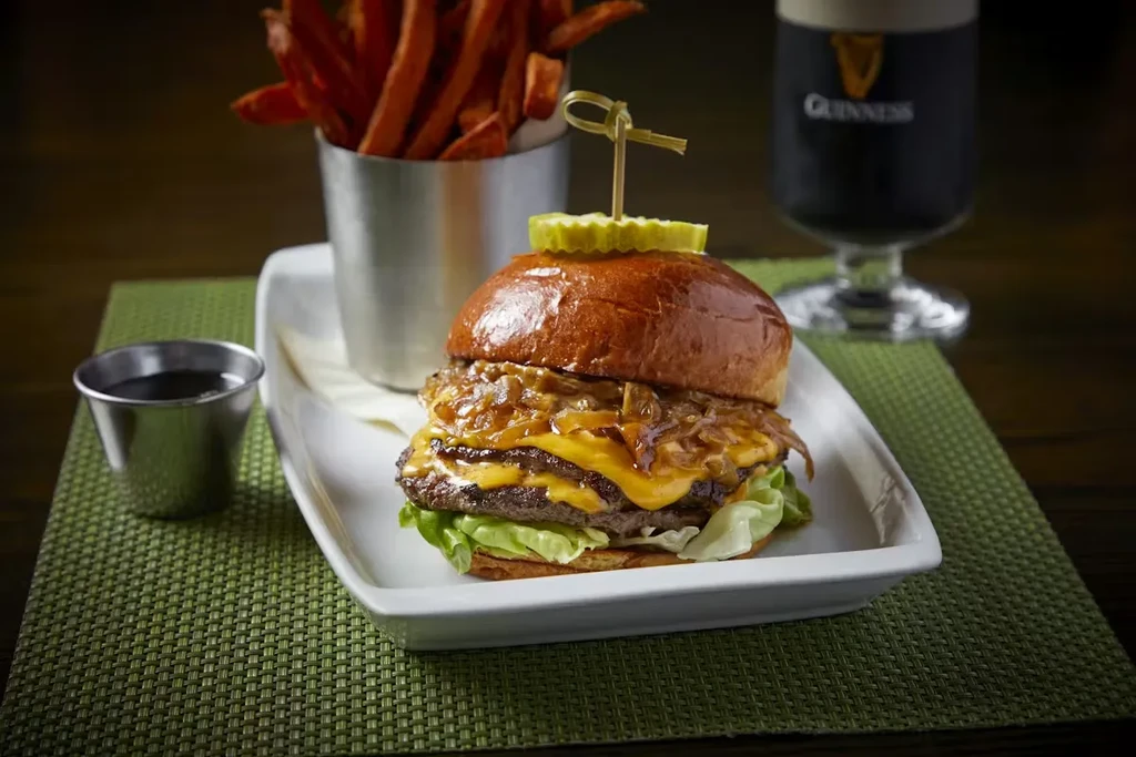 Double cheeseburger with sweet potato fries, dipping sauce, and Guinness beer.