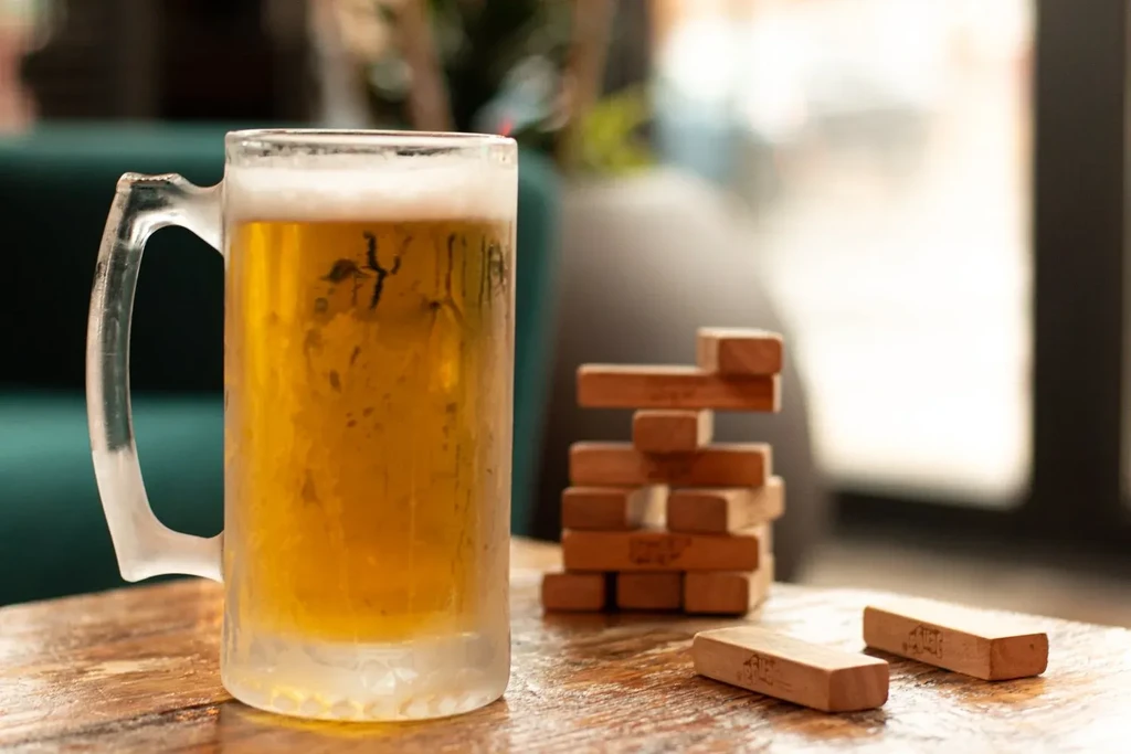 Frosty mug of beer on a wooden table with Jenga blocks.