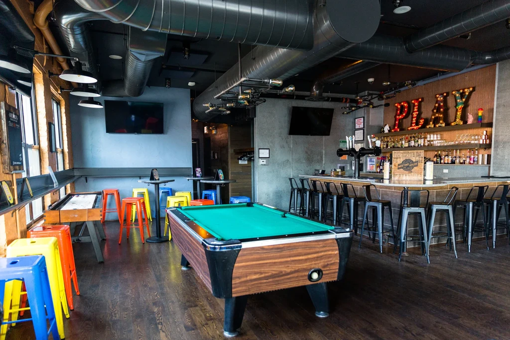 Modern bar with a pool table, shuffleboard, and stocked bar.