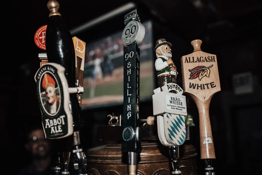 Close-up of four beer tap handles in a dimly lit bar.