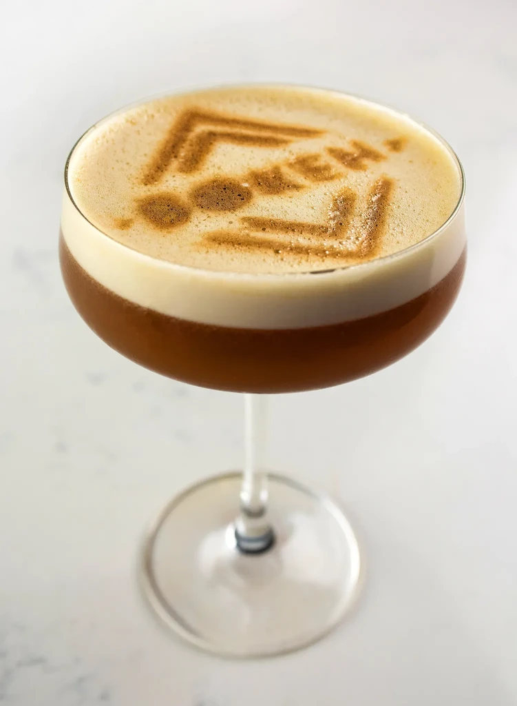 Drink in stemmed glass with latte art on foam.