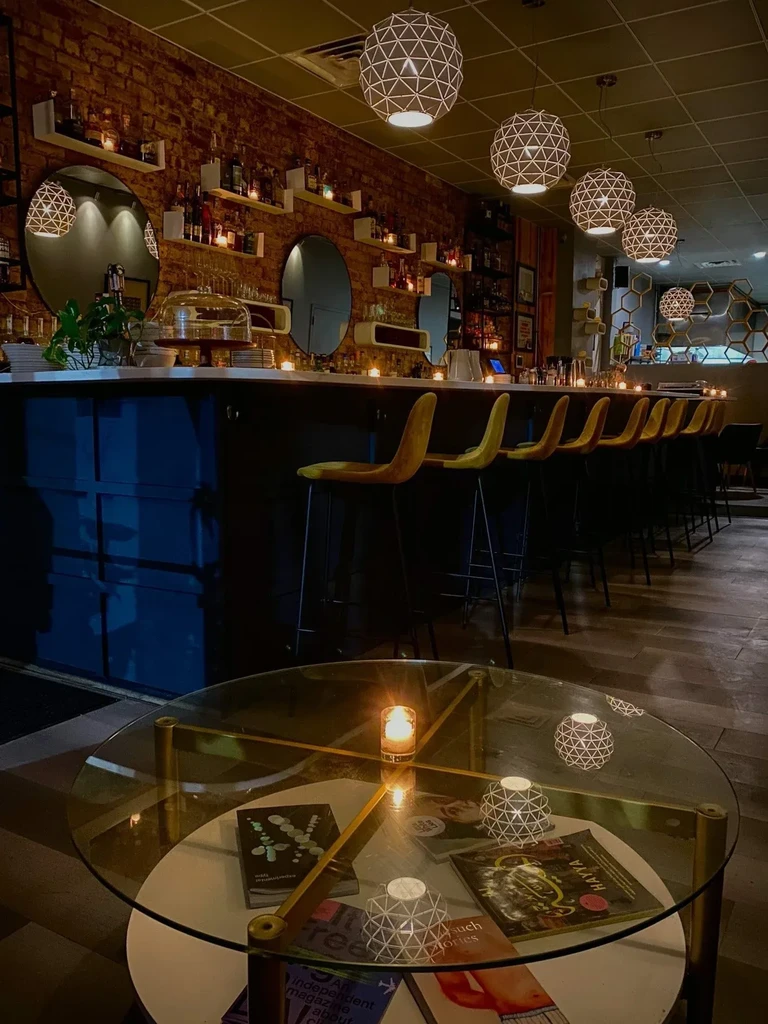 Dimly lit bar with brick wall, bottles, mirrors, and spherical lights.