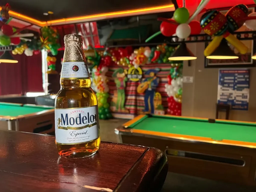 Modelo Especial bottle on bar with mariachi-themed decorations and pool tables.