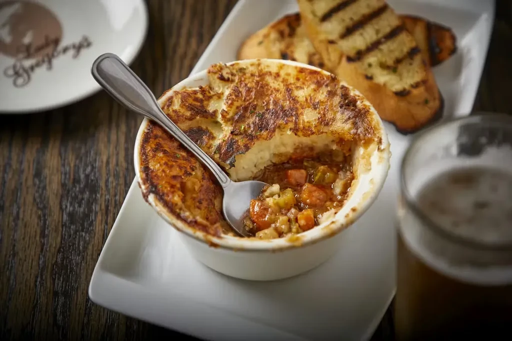 Shepherd's pie with a spoon, grilled bread, and beer.