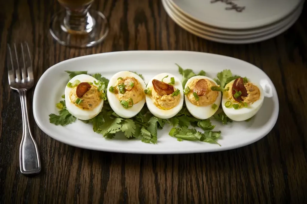 Five deviled eggs on a platter, garnished with green onions.
