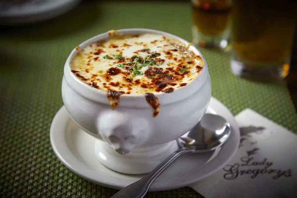 French onion soup in a white crock with melted cheese.