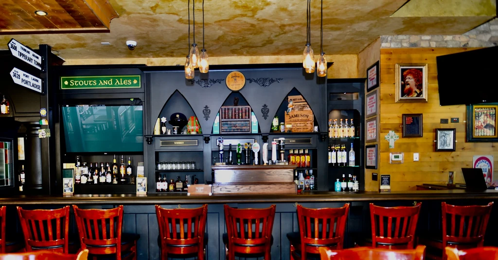 Interior of a well-stocked Irish pub bar with red stools.