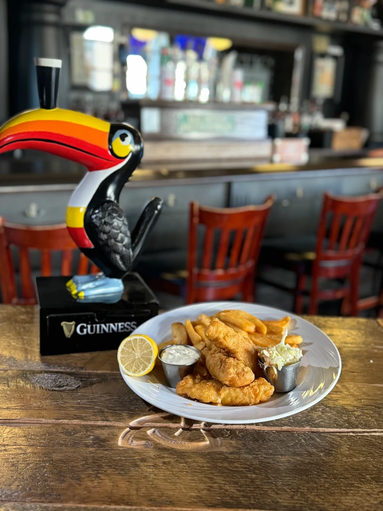 Fried fish and chips with tartar sauce, coleslaw, and a Guinness tap.