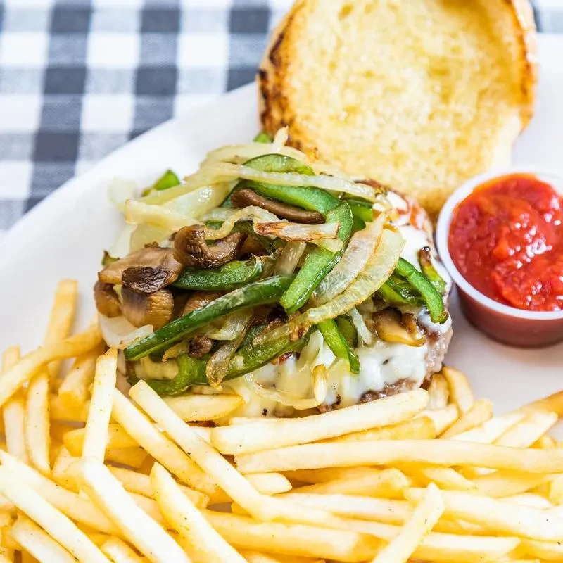 Gourmet burger with melted cheese, vegetables, and French fries.