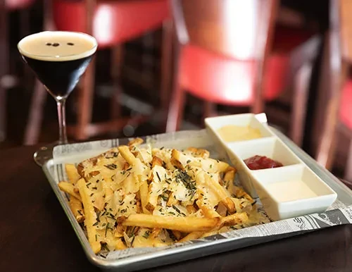 French fries with melted cheese, dipping sauces, and an espresso martini.