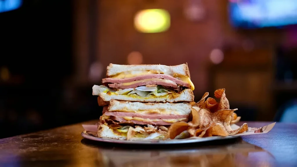Stacked sandwich with chips on a metal plate.