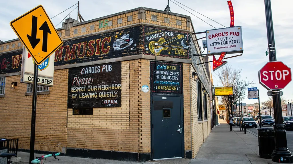 Exterior of Carol's Pub, a brick building with murals and signs.