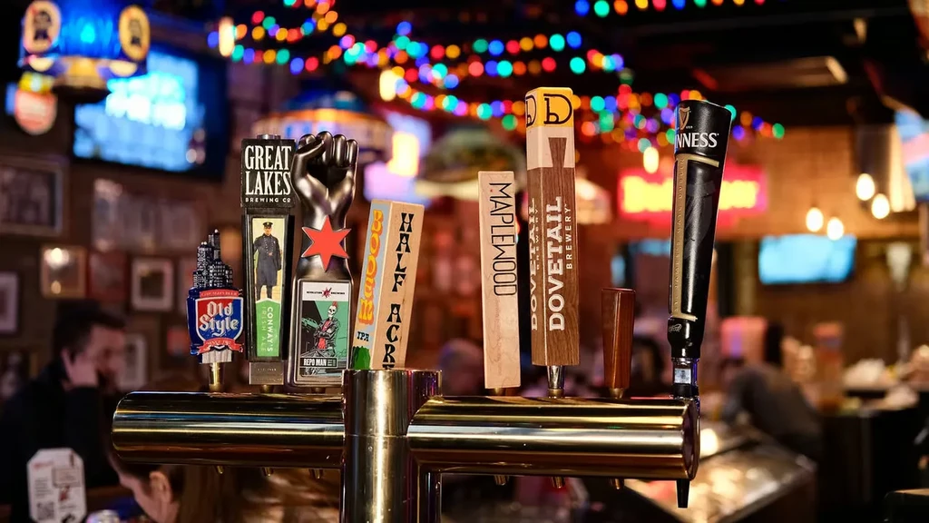 Beer tap handles on a golden dispenser in a dimly lit bar.