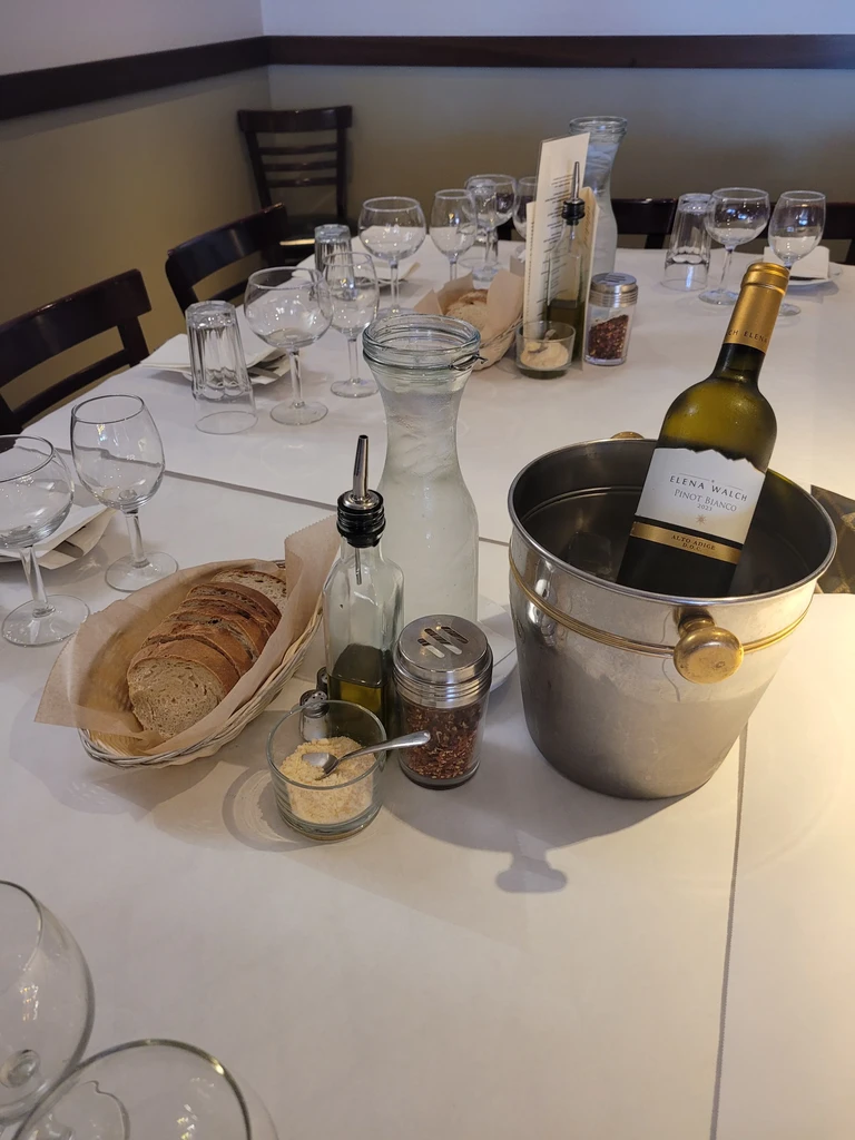 Dining table set with wine, water, bread, cheese, and olive oil.